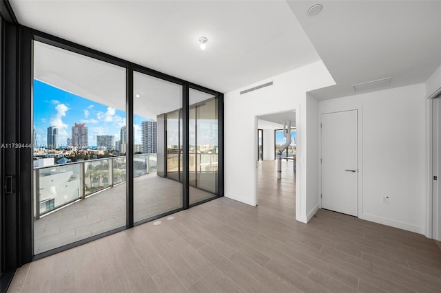 spare room with expansive windows and hardwood / wood-style flooring