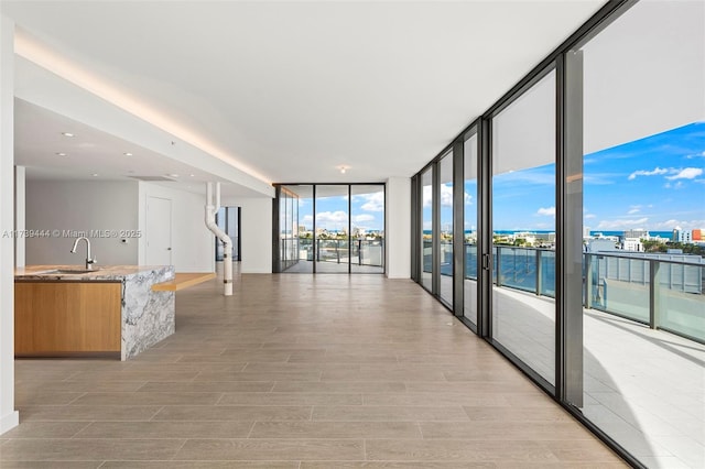 interior space featuring light wood-type flooring, sink, a wall of windows, and a water view