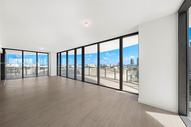 empty room with hardwood / wood-style flooring and a wall of windows