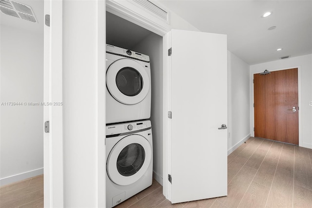 clothes washing area with light hardwood / wood-style floors and stacked washer / dryer