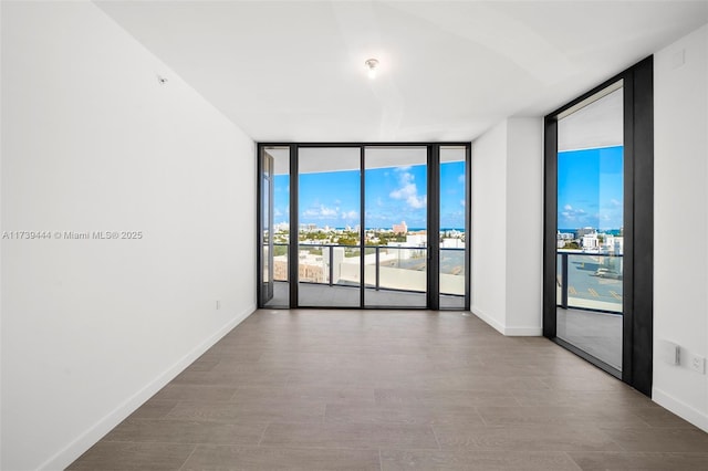 unfurnished room featuring a wall of windows and light hardwood / wood-style floors