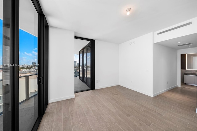 spare room featuring floor to ceiling windows and light hardwood / wood-style floors