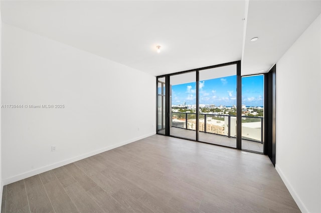 empty room featuring hardwood / wood-style floors and a wall of windows