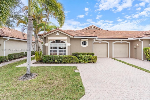 mediterranean / spanish house featuring a garage and a front lawn