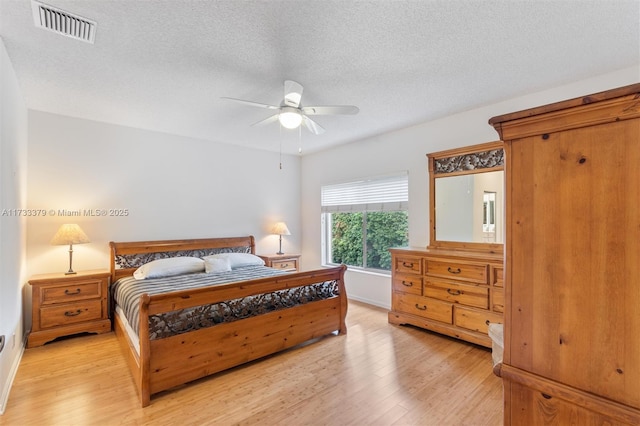 bedroom with ceiling fan, a textured ceiling, and light hardwood / wood-style floors