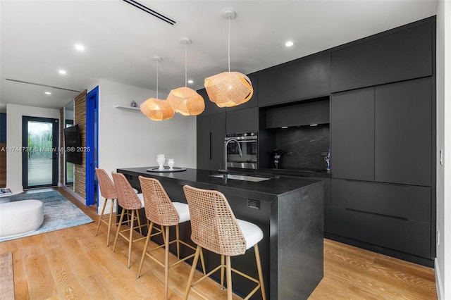 kitchen featuring pendant lighting, a breakfast bar, light wood-type flooring, and oven