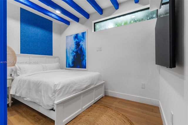 bedroom with beamed ceiling and hardwood / wood-style flooring