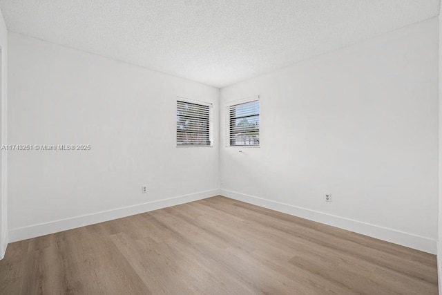 empty room with light hardwood / wood-style floors and a textured ceiling