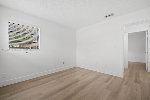 empty room featuring a textured ceiling and light wood-type flooring