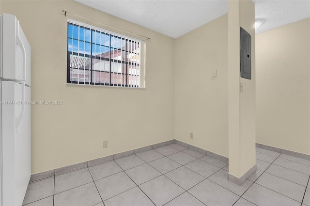 spare room with electric panel, a textured ceiling, and light tile patterned flooring