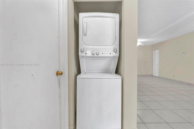 clothes washing area with stacked washer and dryer, a textured ceiling, and light tile patterned flooring