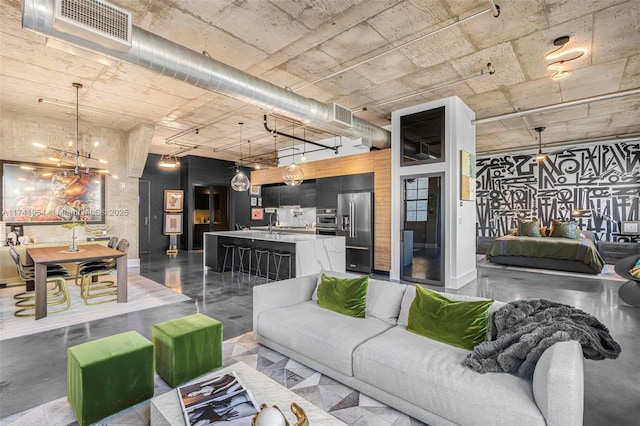 living room with concrete flooring and an inviting chandelier