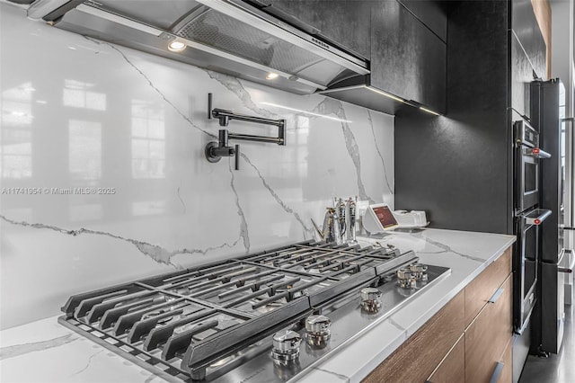 kitchen featuring light stone countertops, stainless steel gas cooktop, and decorative backsplash