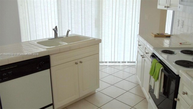575 SE 29th Dr, Homestead, FL 33033 - kitchen with range with electric stovetop, tile countertops, white cabinets, a sink, and dishwasher