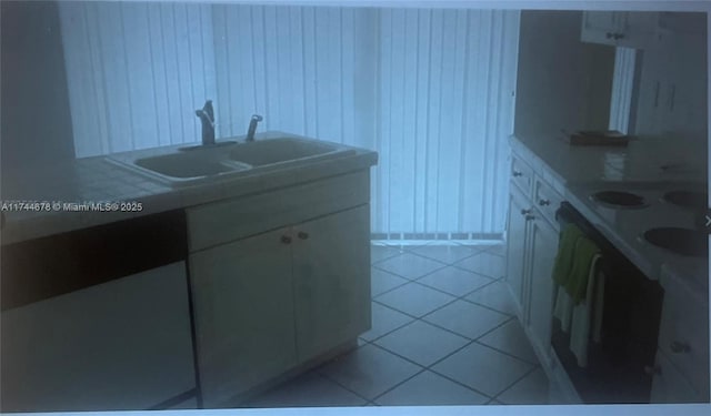 kitchen with light countertops, white cabinets, a sink, and light tile patterned floors