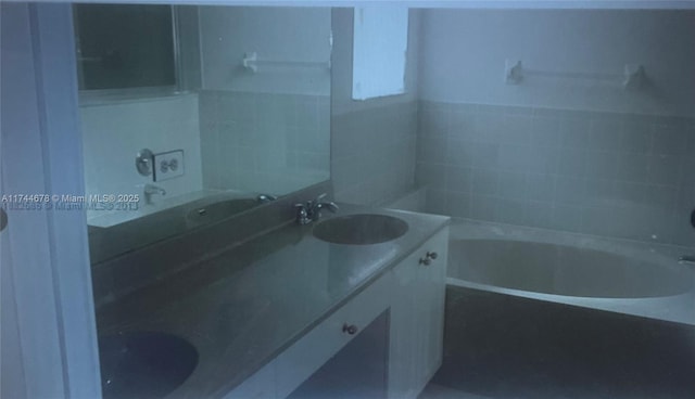 bathroom with double vanity, a sink, and a bathing tub