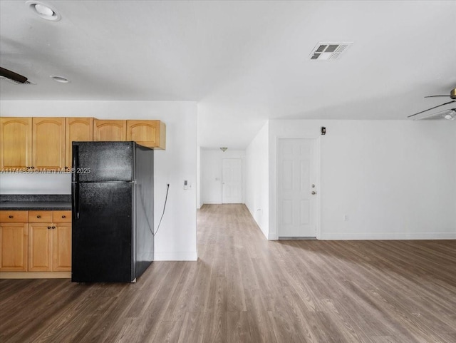 kitchen featuring black fridge, dark hardwood / wood-style floors, light brown cabinetry, and ceiling fan