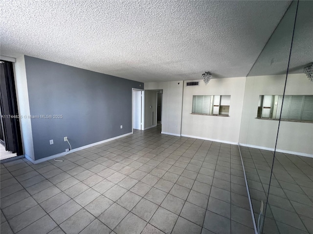 tiled spare room featuring a textured ceiling