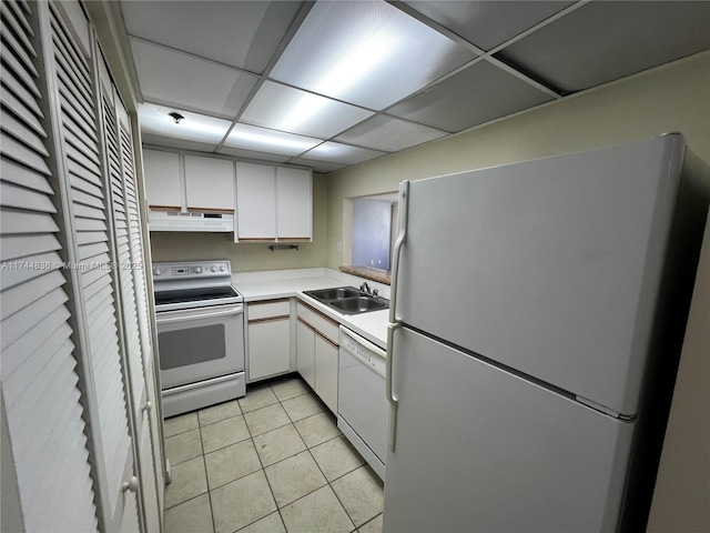 kitchen featuring sink, white cabinetry, a paneled ceiling, light tile patterned floors, and white appliances