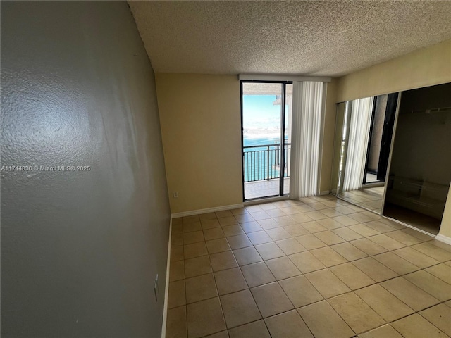 empty room with light tile patterned floors and a textured ceiling