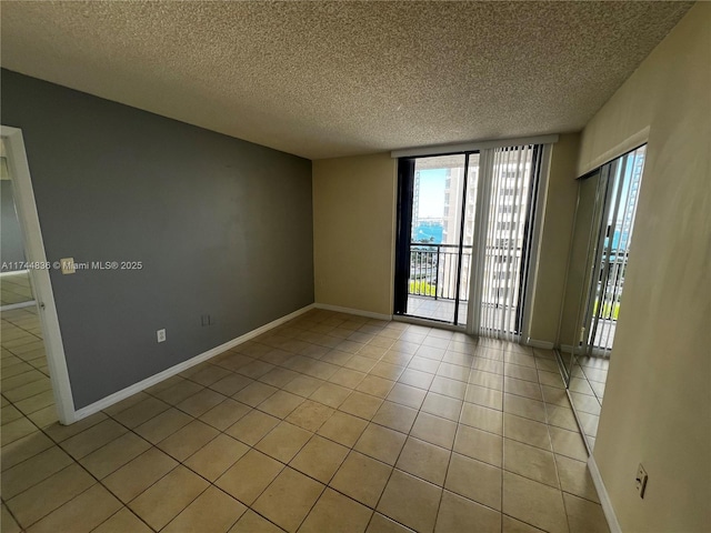 tiled empty room featuring floor to ceiling windows and a textured ceiling