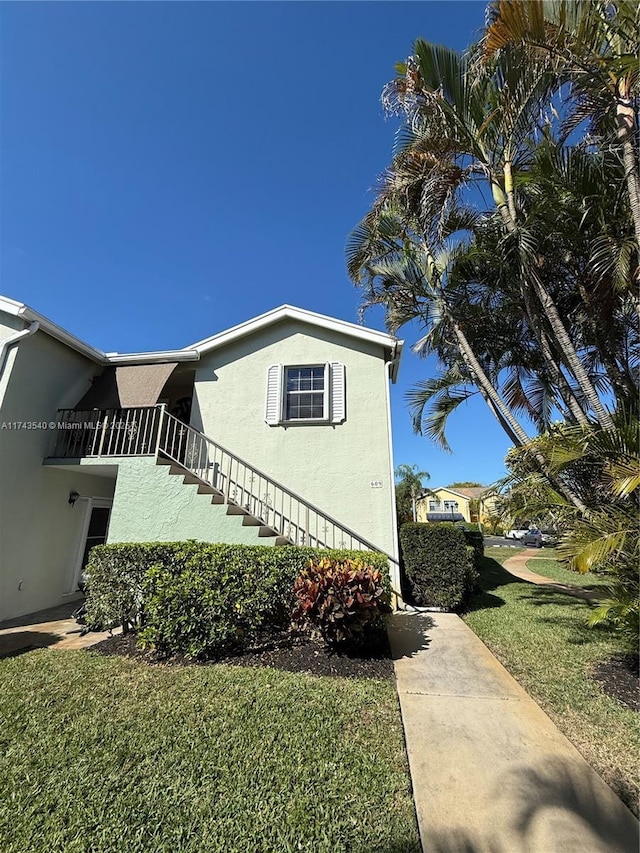 609 Waterside Dr Unit 609, Hypoluxo, FL 33462 - view of side of property featuring stucco siding, stairs, and a yard