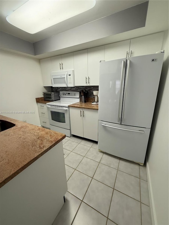 609 Waterside Dr Unit 609, Hypoluxo, FL 33462 - kitchen with white appliances, white cabinets, light tile patterned floors, dark countertops, and decorative backsplash