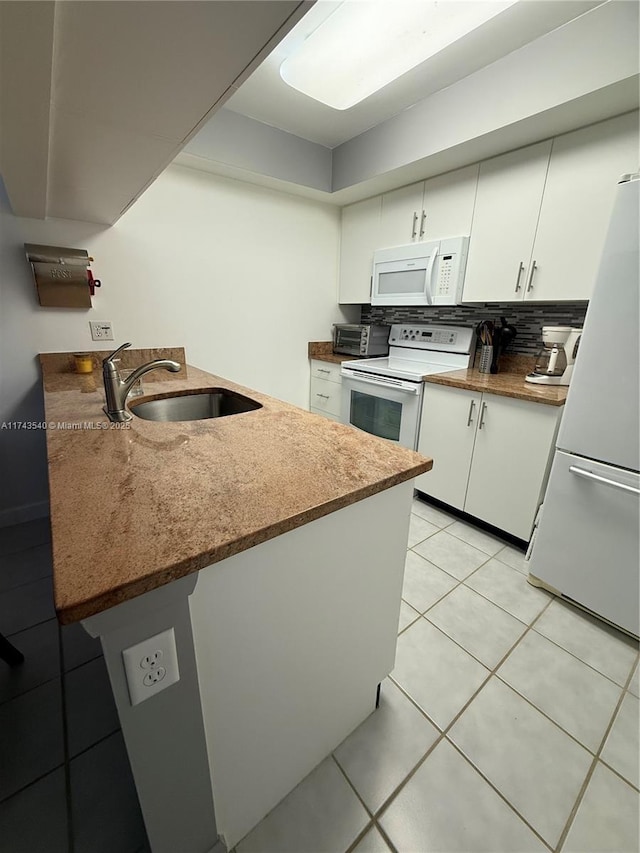 609 Waterside Dr Unit 609, Hypoluxo, FL 33462 - kitchen featuring white appliances, white cabinets, light tile patterned floors, a peninsula, and tasteful backsplash