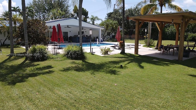 view of swimming pool featuring ceiling fan, a yard, and a patio area