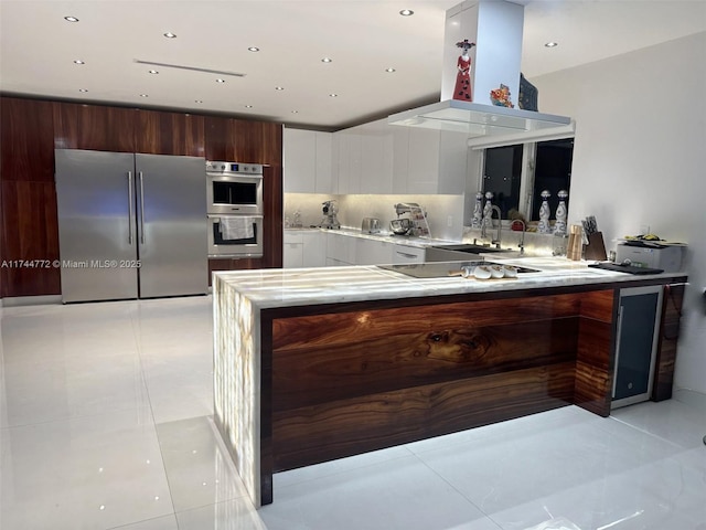 kitchen with sink, kitchen peninsula, island exhaust hood, stainless steel appliances, and white cabinets