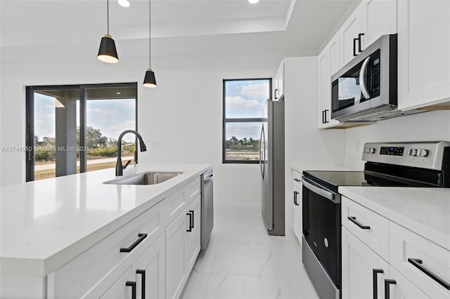 kitchen with pendant lighting, sink, stainless steel appliances, and white cabinets