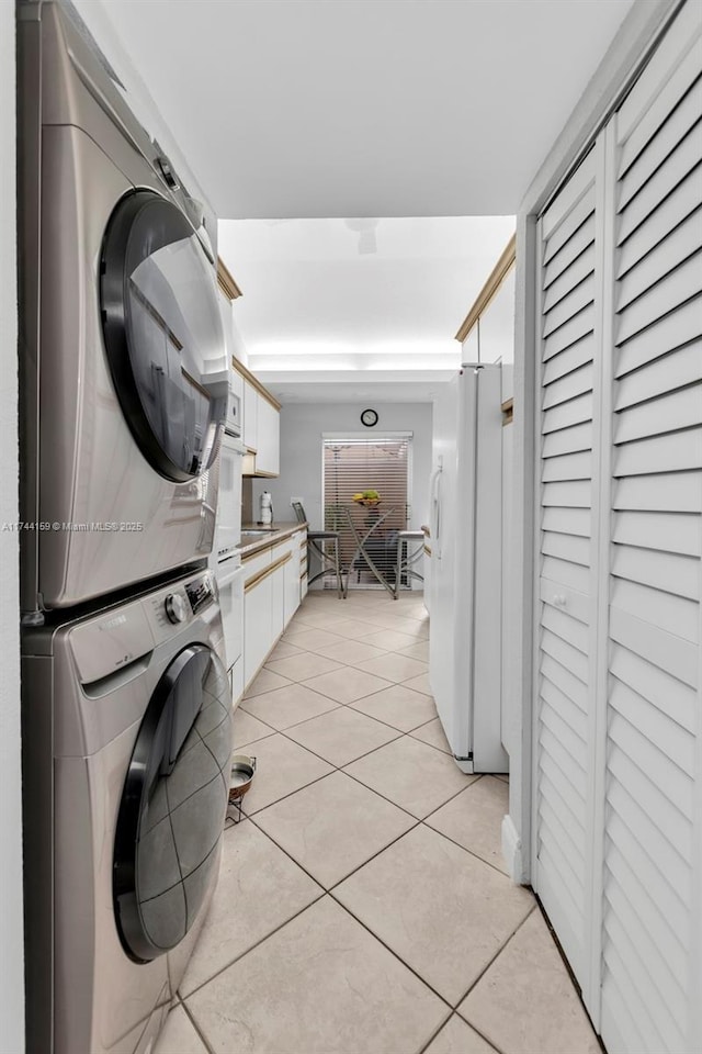 washroom with light tile patterned flooring and stacked washer / drying machine