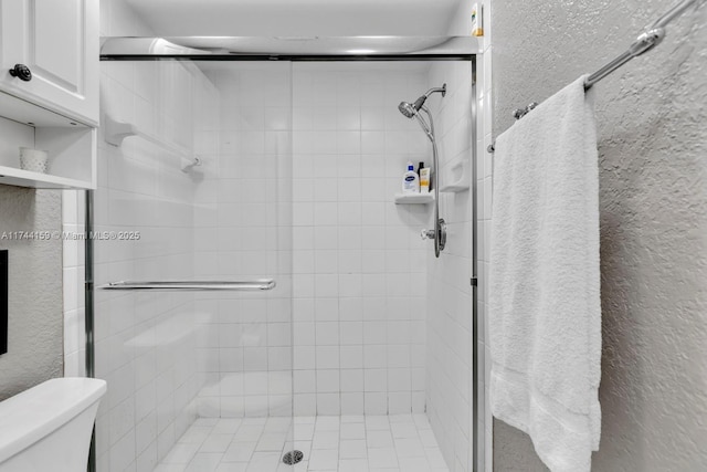 bathroom featuring toilet and a shower with door