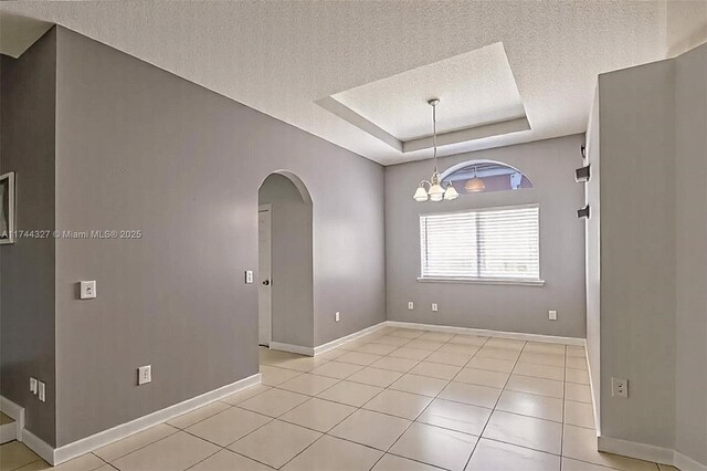 2120 SE 17th Ave, Homestead, FL 33035 - unfurnished room featuring a textured ceiling, arched walkways, a tray ceiling, light tile patterned flooring, and a chandelier