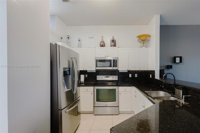 2120 SE 17th Ave, Homestead, FL 33035 - kitchen featuring appliances with stainless steel finishes, white cabinets, light tile patterned floors, backsplash, and dark stone counters