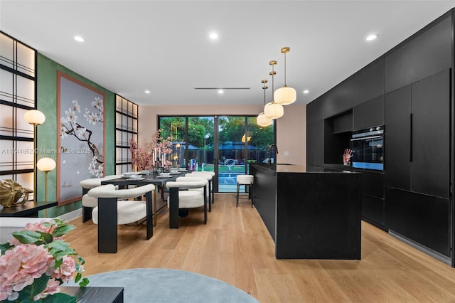 kitchen with sink, hanging light fixtures, a center island, light hardwood / wood-style floors, and oven