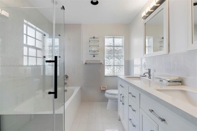 full bathroom featuring tile walls, tile patterned flooring, vanity, shower with separate bathtub, and toilet