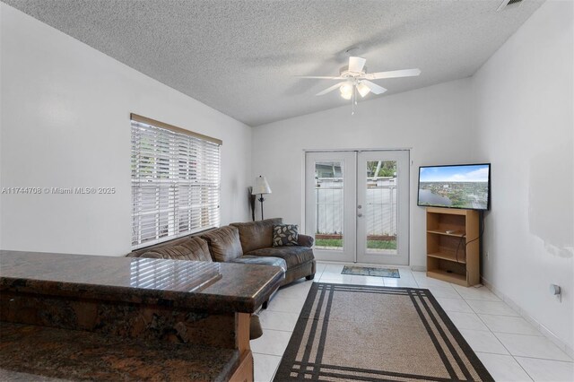 tiled living room featuring ceiling fan, lofted ceiling, a textured ceiling, and french doors