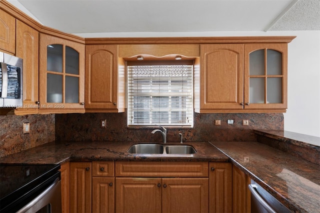 kitchen featuring appliances with stainless steel finishes, sink, backsplash, and dark stone counters