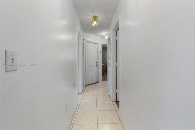 hall featuring a textured ceiling and light tile patterned floors