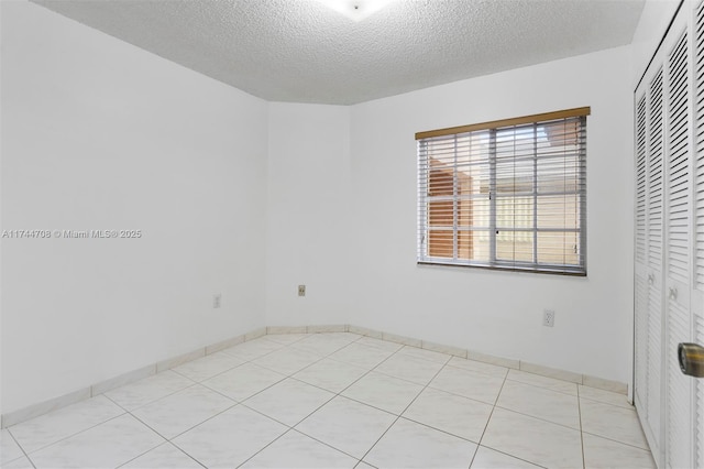 empty room with light tile patterned flooring and a textured ceiling