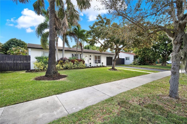 ranch-style home featuring a garage, fence, a front lawn, and stucco siding