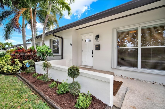 view of exterior entry featuring brick siding and stucco siding