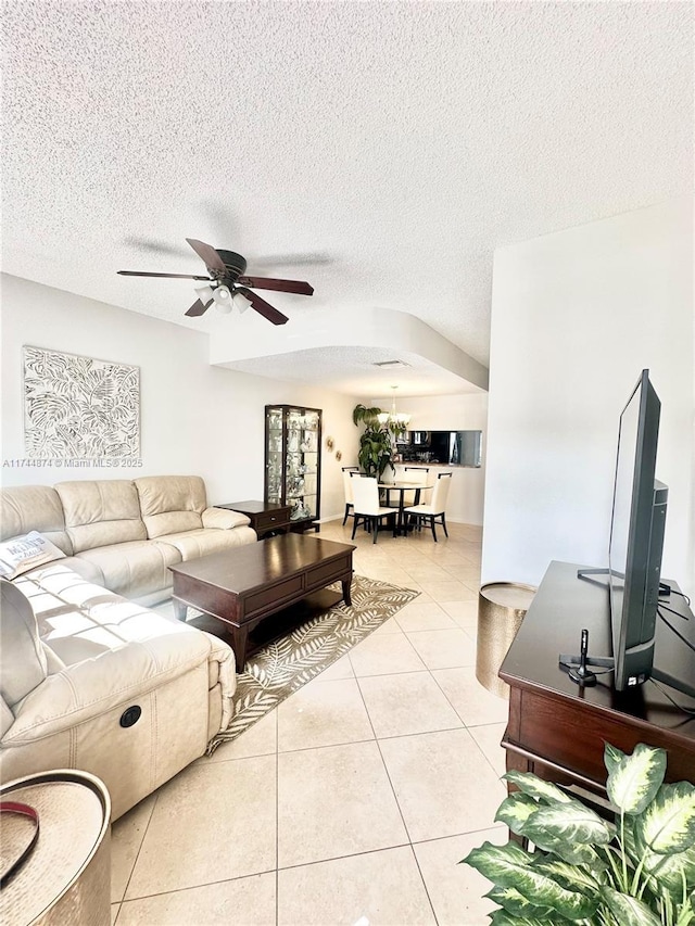 tiled living room with ceiling fan and a textured ceiling