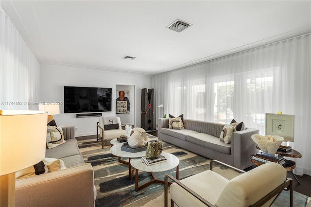 living room with baseboards, visible vents, and ornamental molding