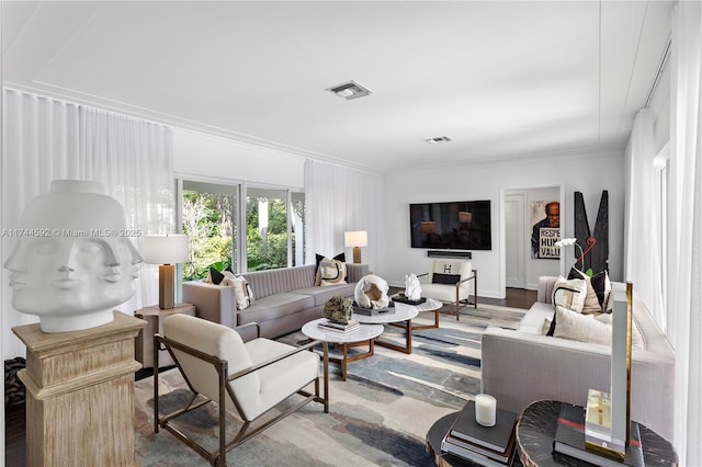 living area with visible vents, crown molding, and wood finished floors