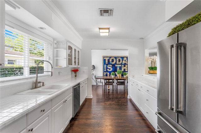 kitchen with sink, white cabinets, decorative backsplash, stainless steel appliances, and crown molding