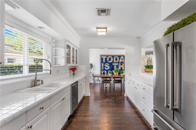 kitchen with ornamental molding, a sink, stainless steel appliances, and visible vents