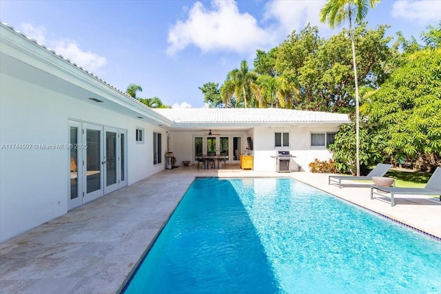 pool with french doors, ceiling fan, a grill, and a patio area