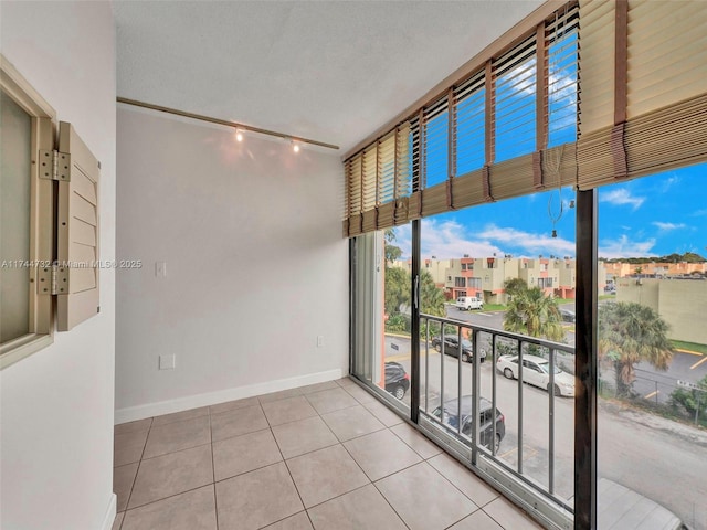 tiled spare room featuring track lighting, floor to ceiling windows, and a textured ceiling